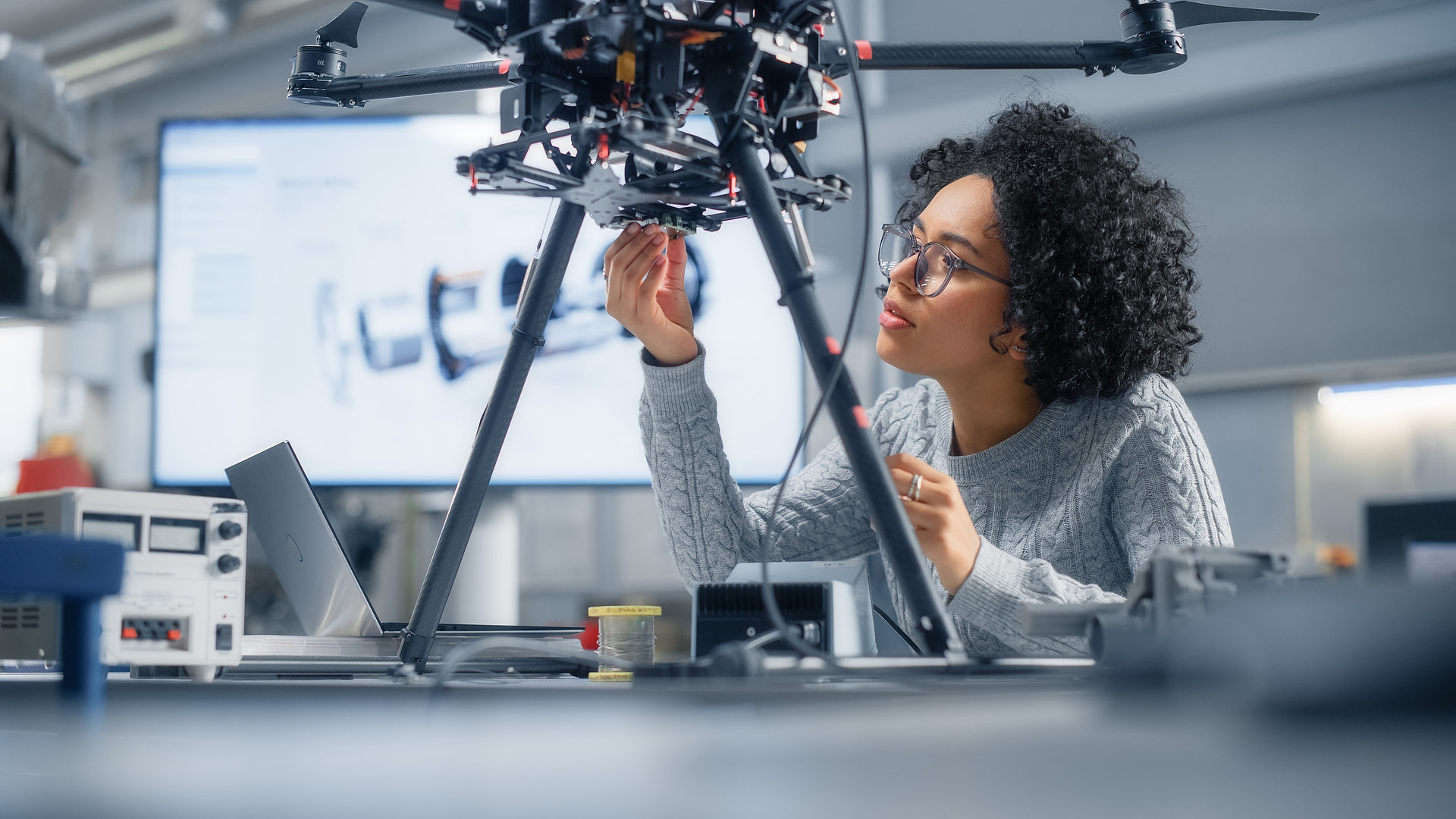 A woman engineer working on a drone, in an engineering workshop.